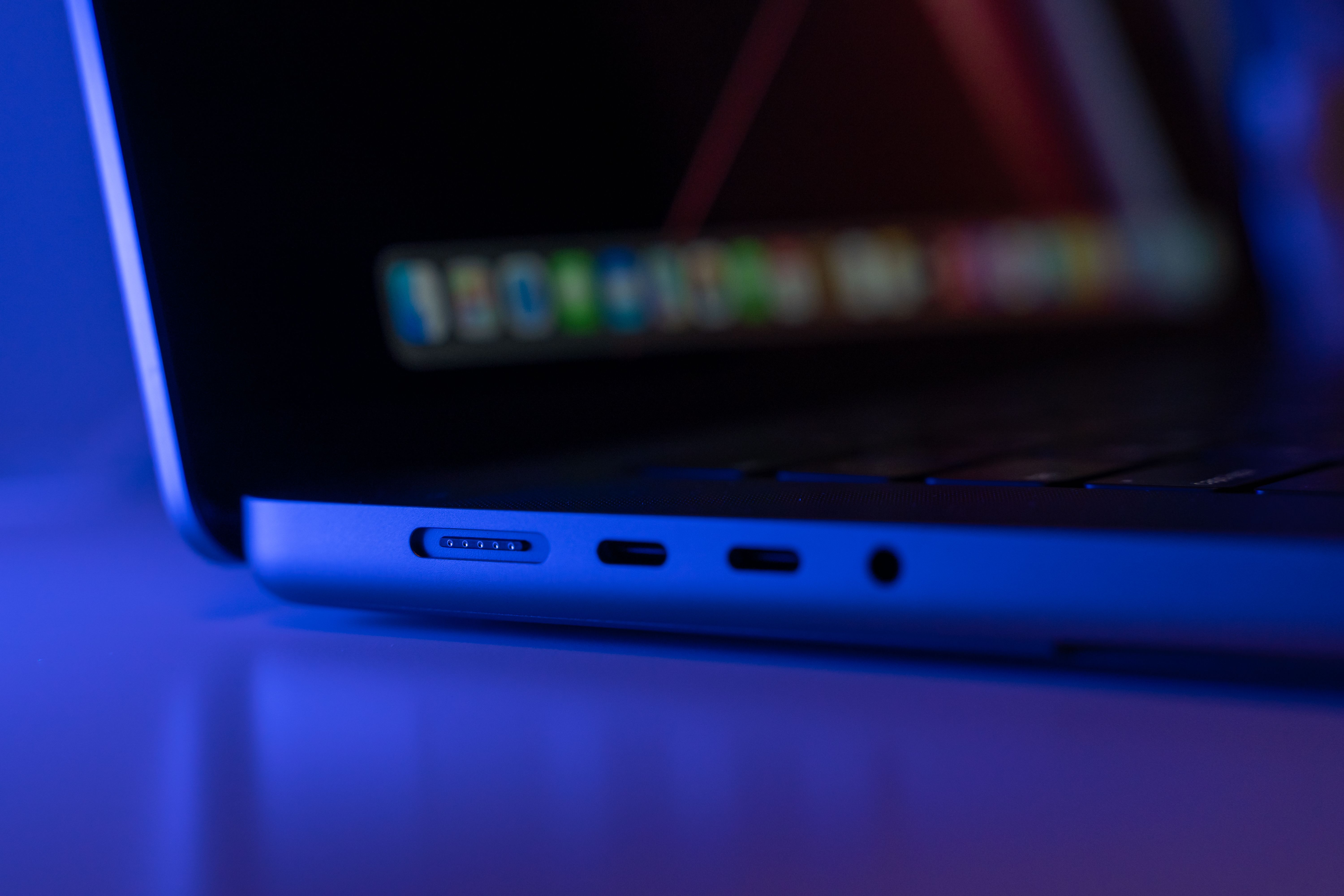 A angled close-up of a sleek laptop with blue ambient lighting highlighting its ports.