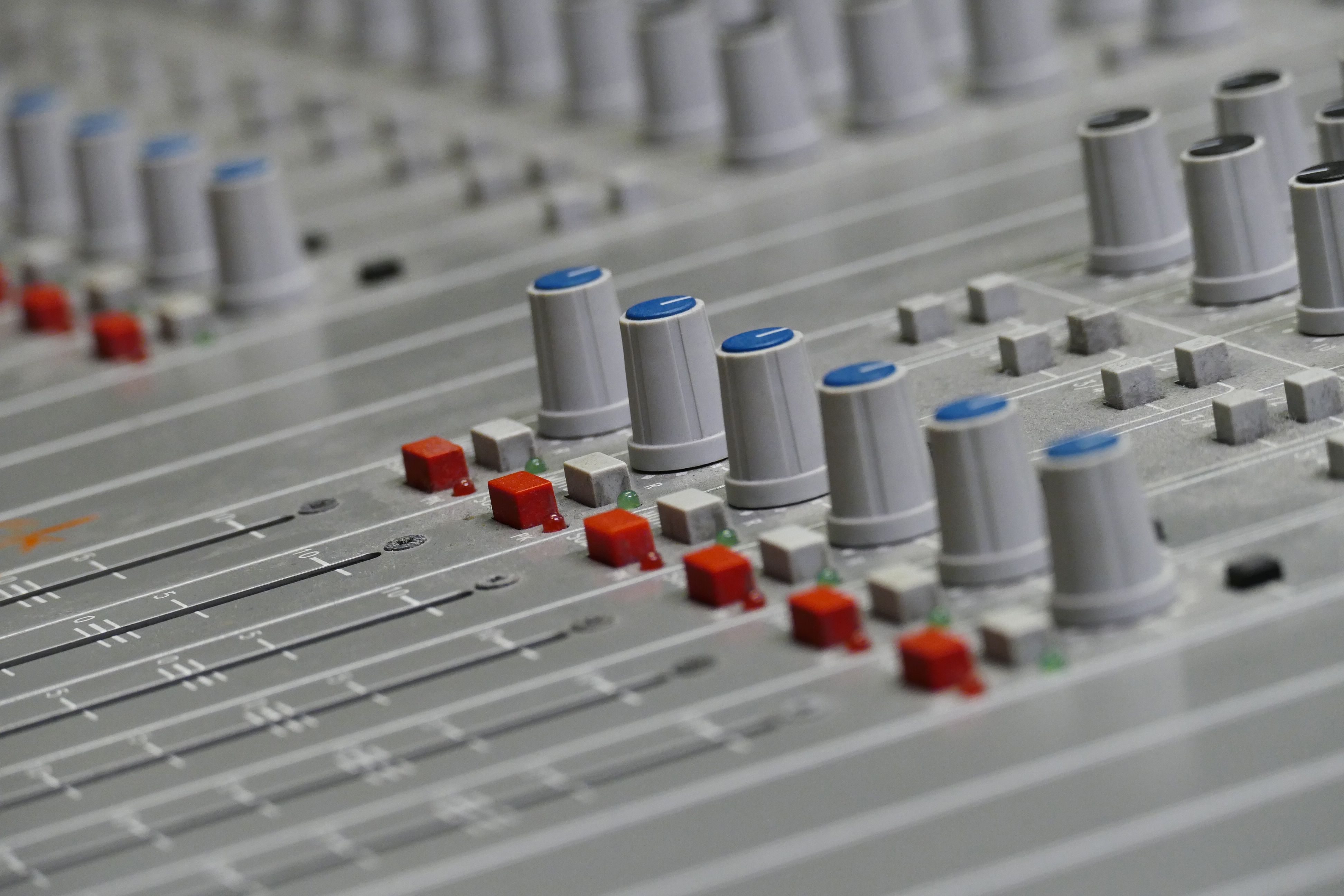 Detailed close-up of an audio mixer with colorful knobs and sliders in a recording studio.