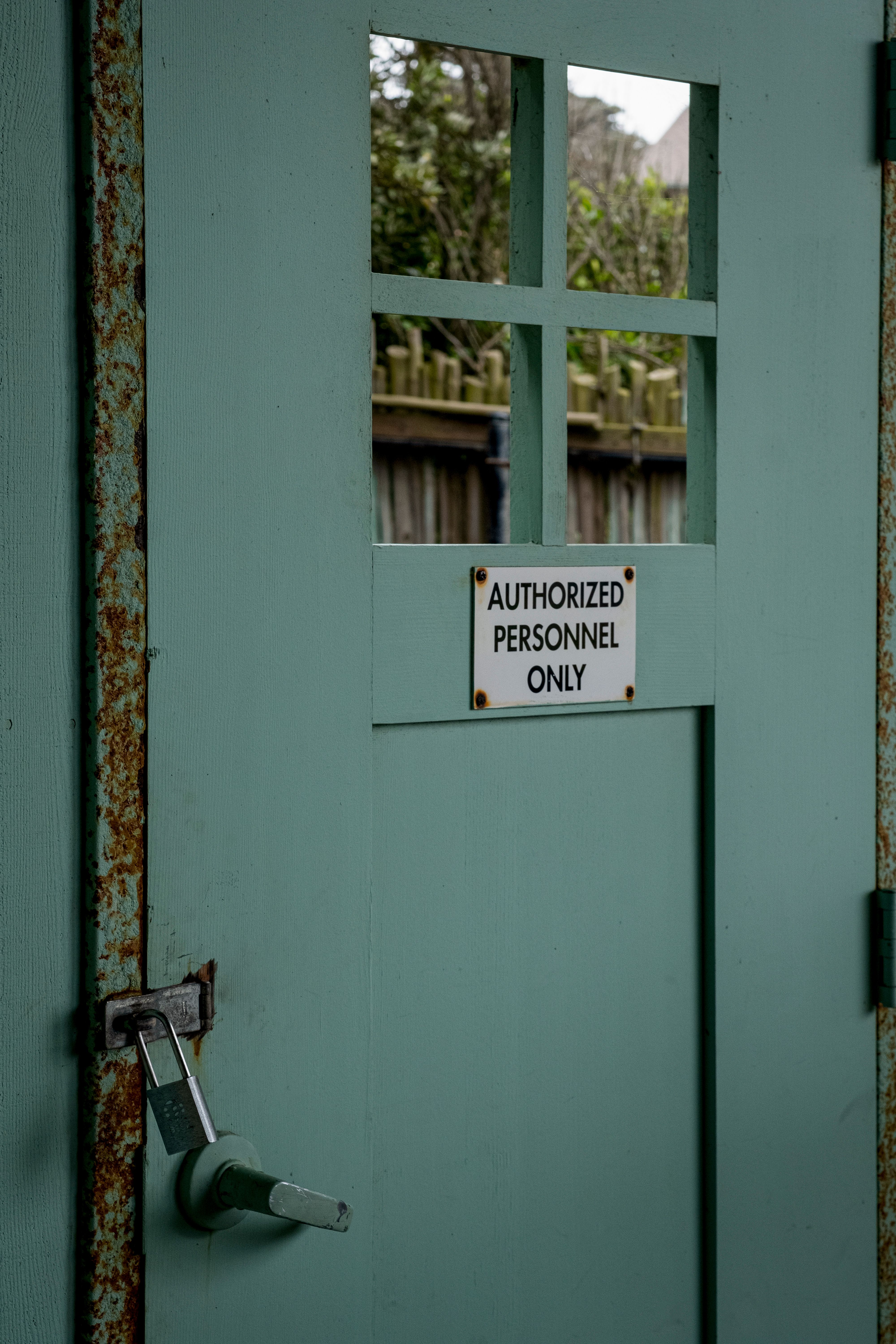 Close-up of a rustic green door with an 'Authorized Personnel Only' sign and padlock.