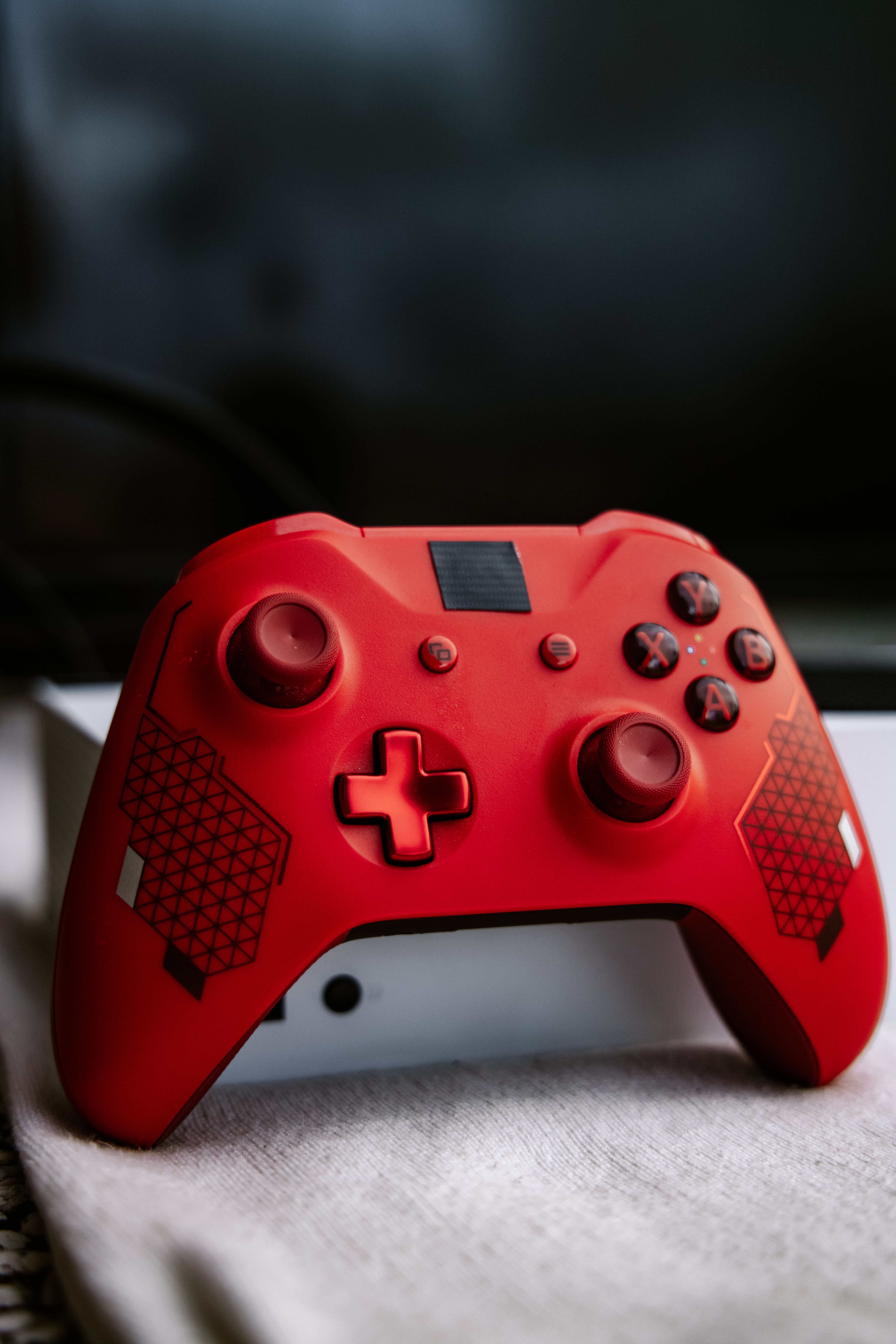 Close-up of a red Xbox game controller on a white surface, perfect for gaming themes.