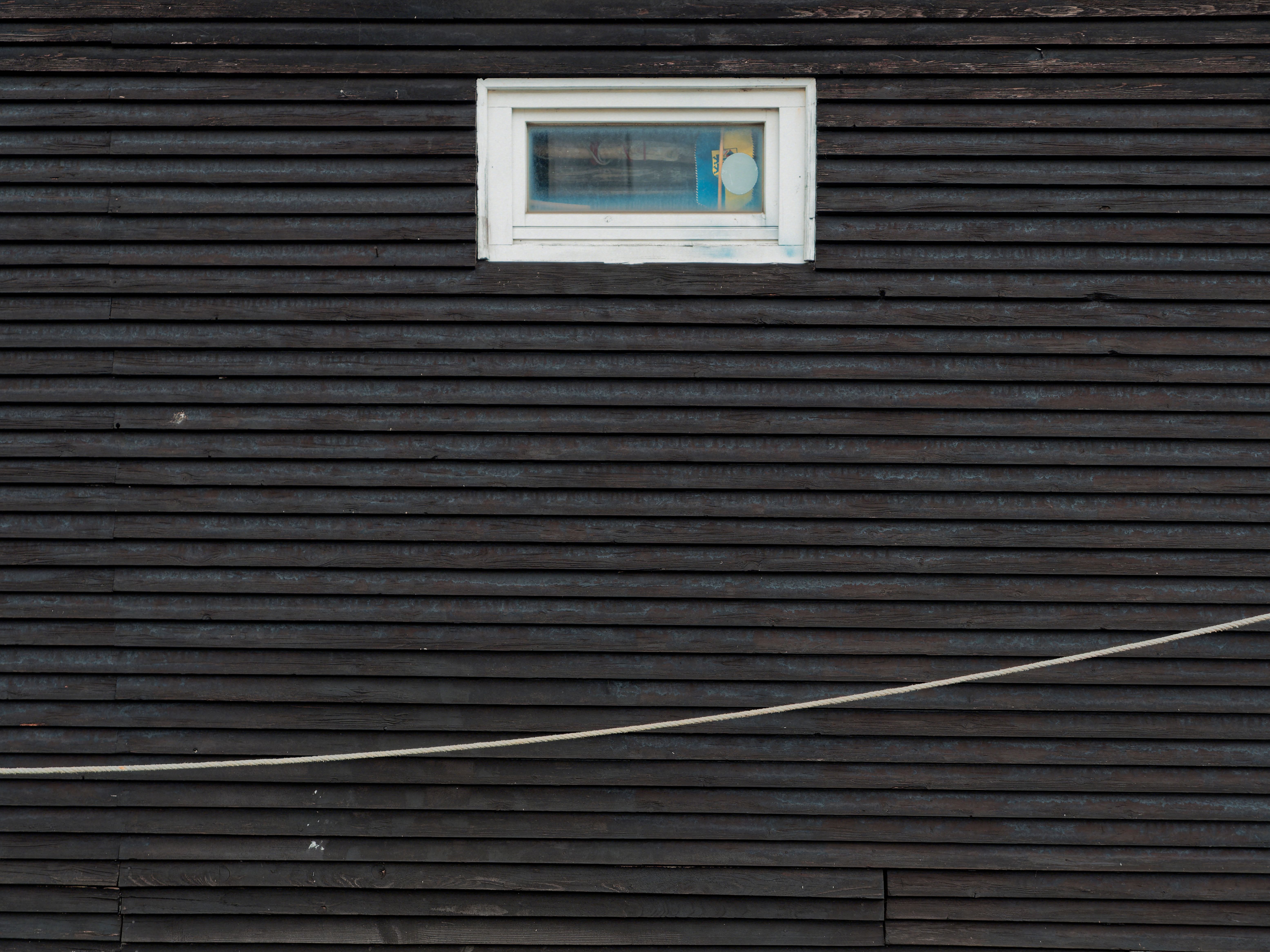 Dark wooden wall featuring a single rectangular window in a minimalist architectural style.