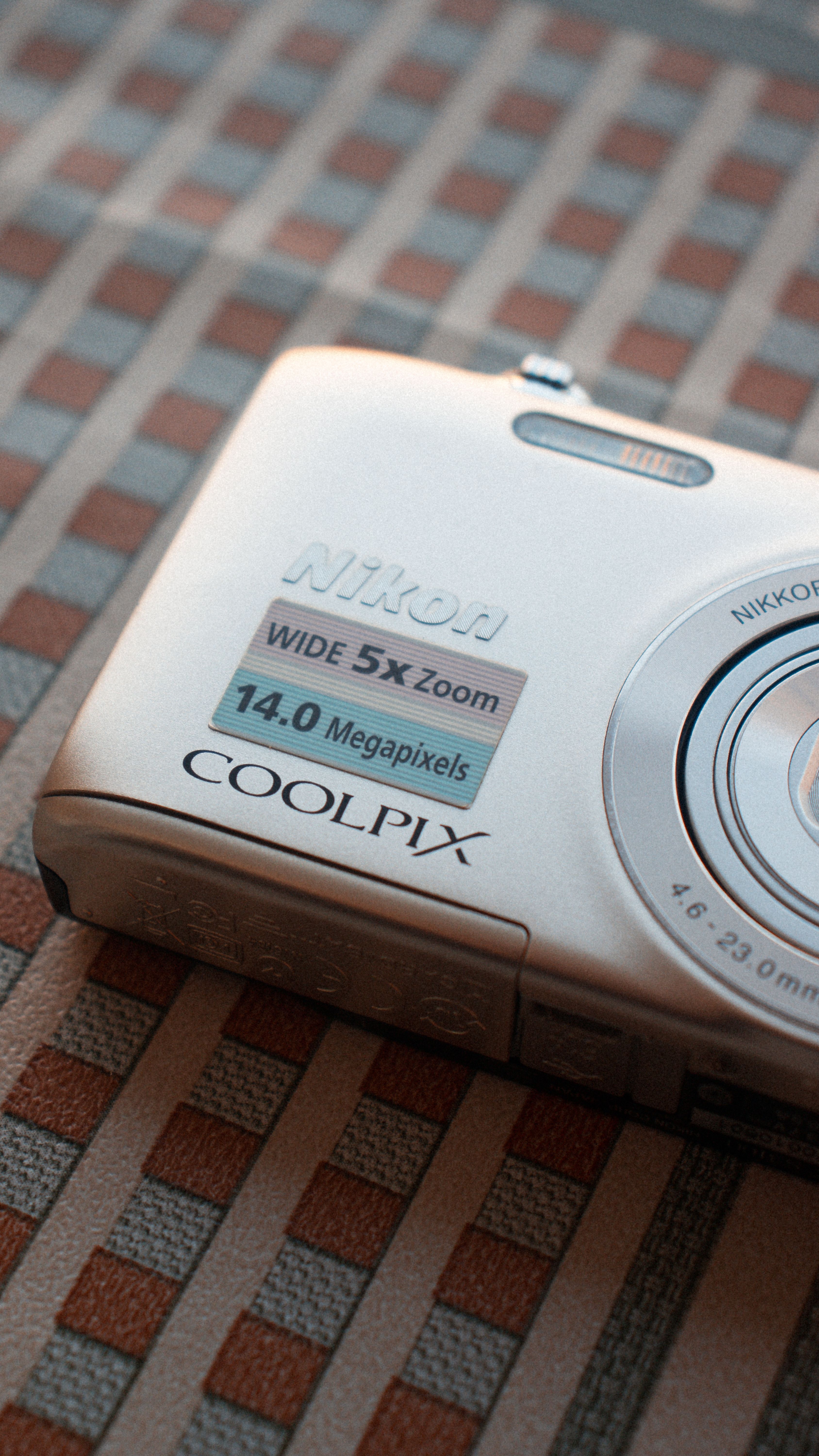 Close-up of a silver digital camera resting on a textured table surface.