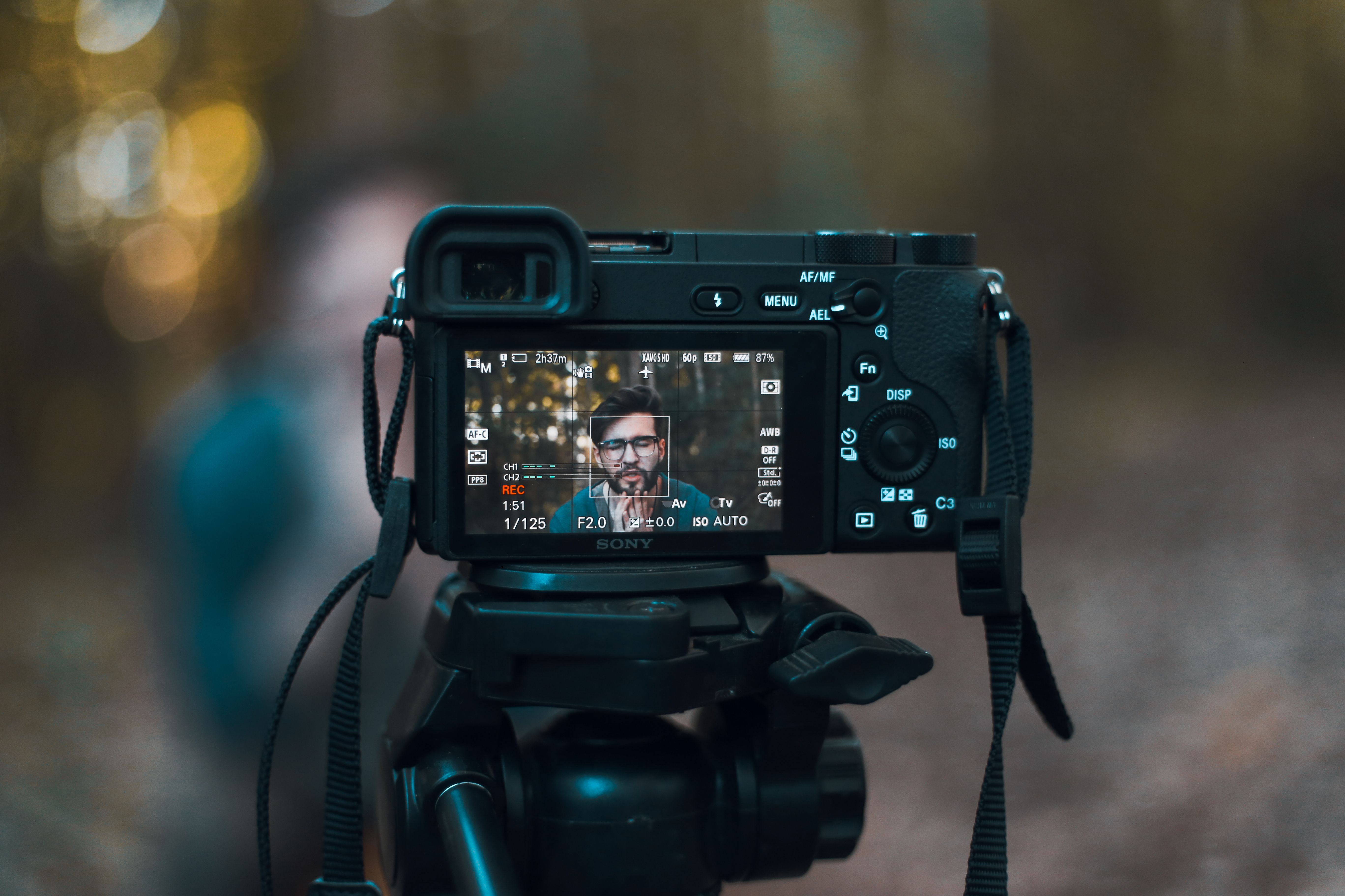 Close-up of a DSLR camera on tripod capturing portrait in an outdoor setting.
