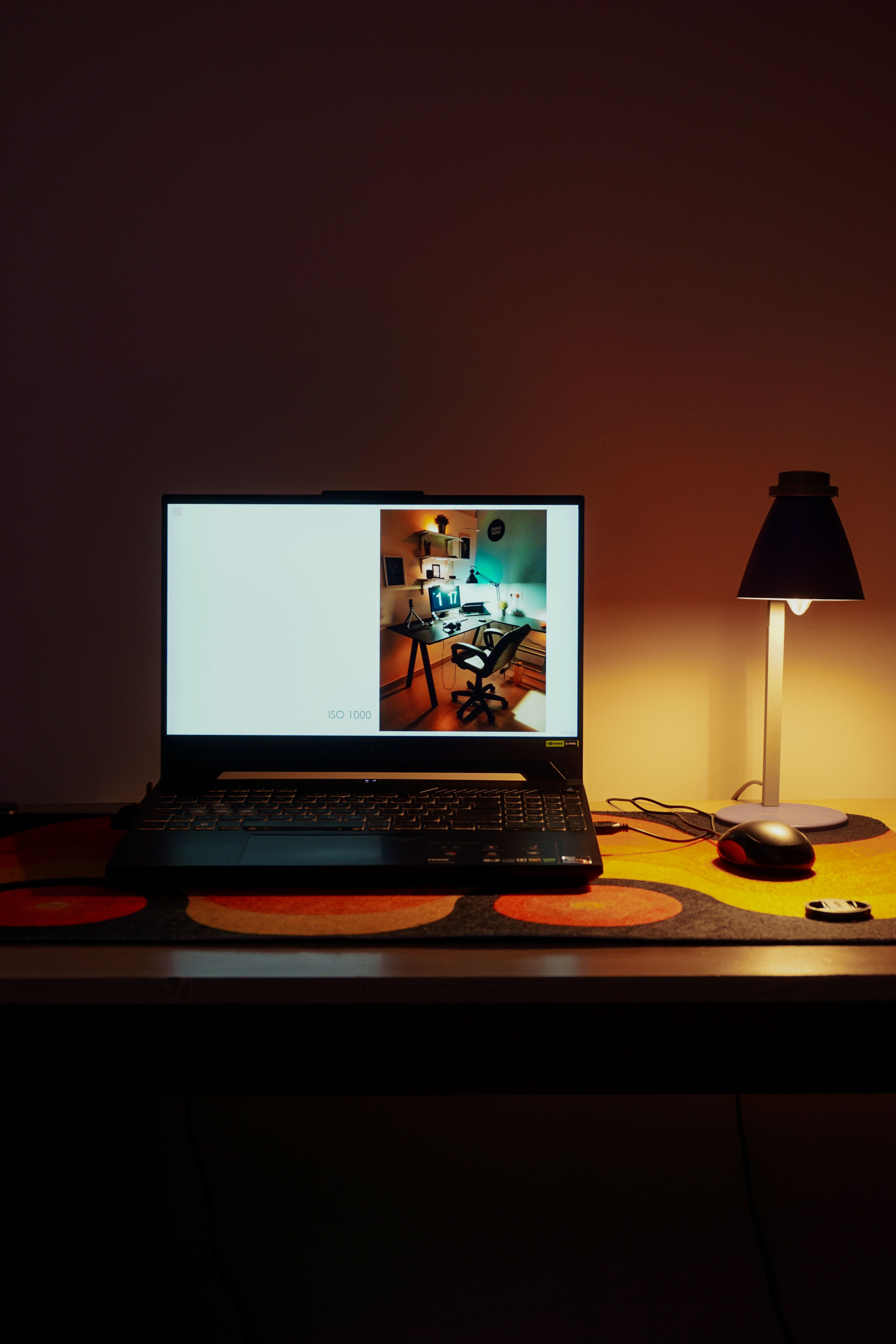A cozy home workspace with a laptop, desk lamp, and warm ambient lighting, perfect for productivity.