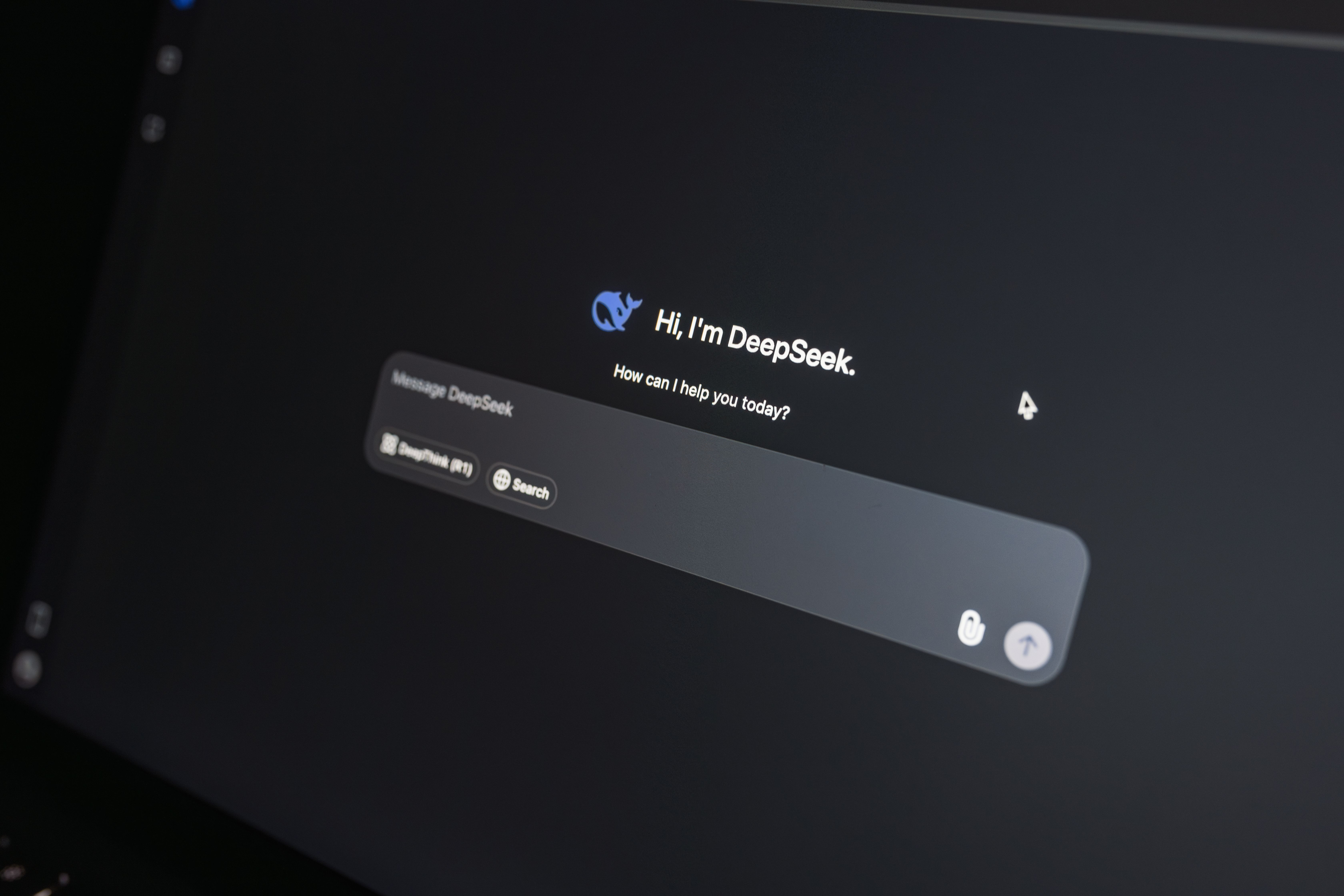 Close-up of DeepSeek AI chat interface on a laptop screen in low light.