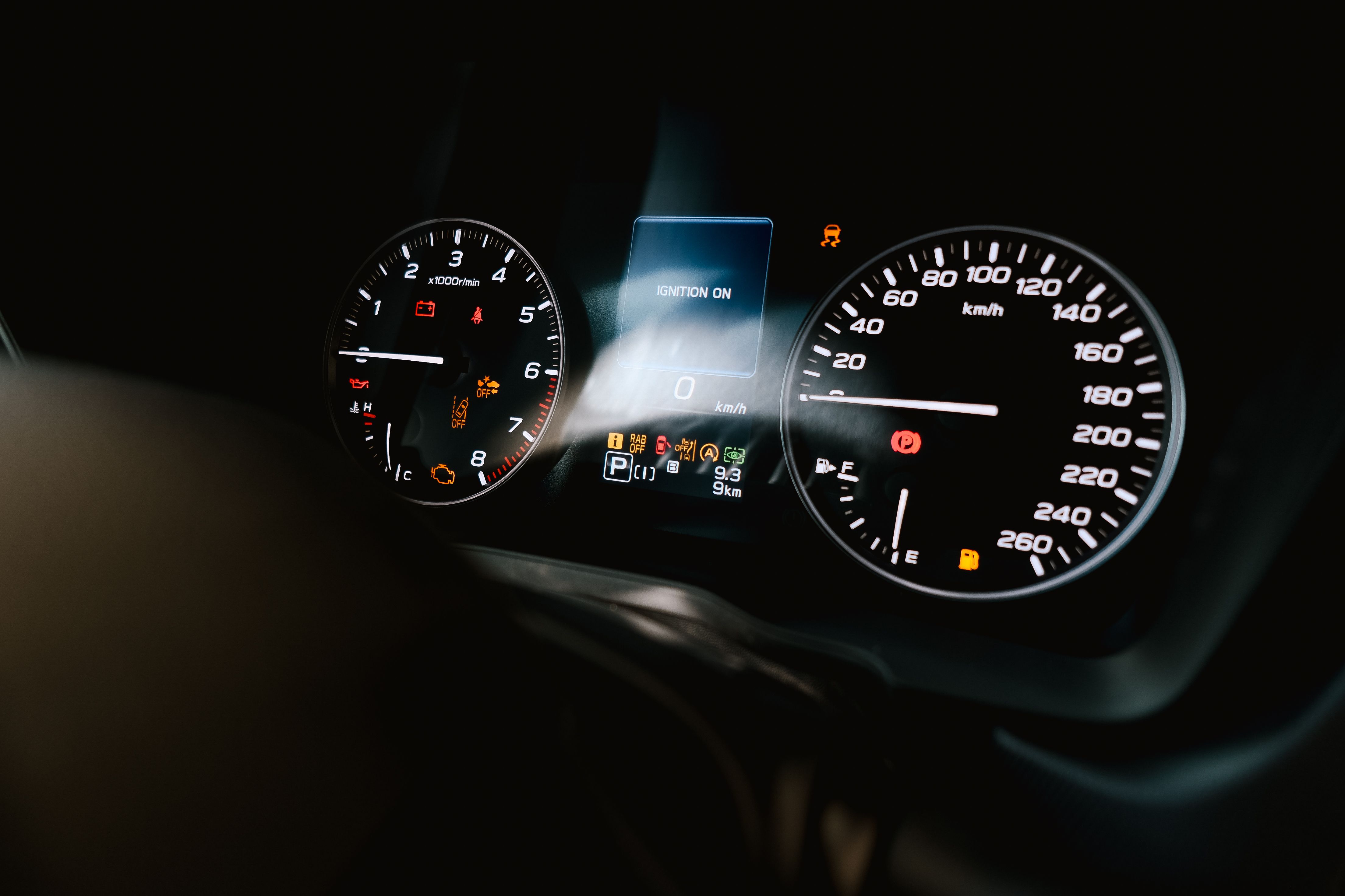Detailed view of a car dashboard showing speedometer, tachometer, and warning lights, with ignition on.