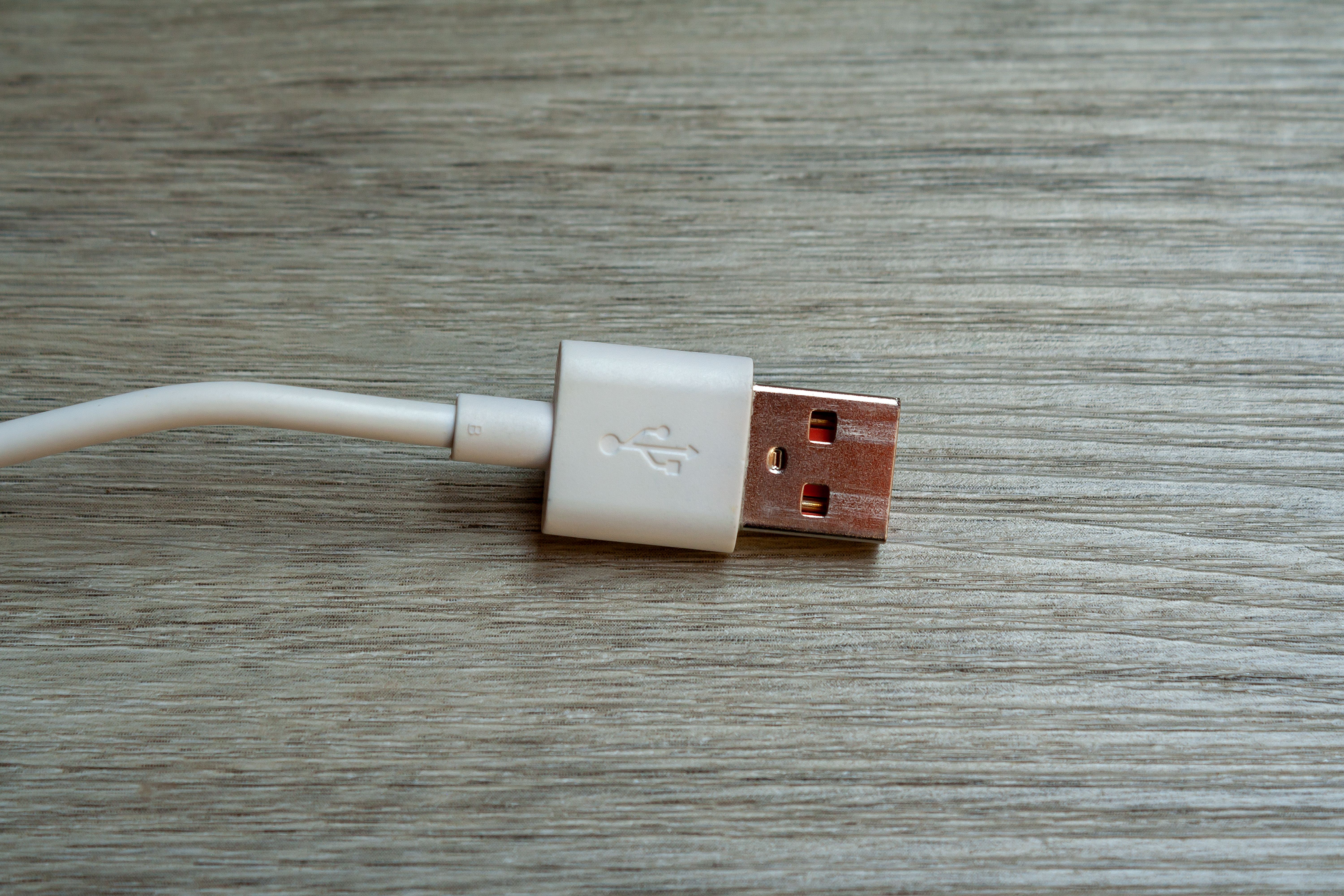 A detailed close-up of a white USB cable connector placed on a wooden surface.