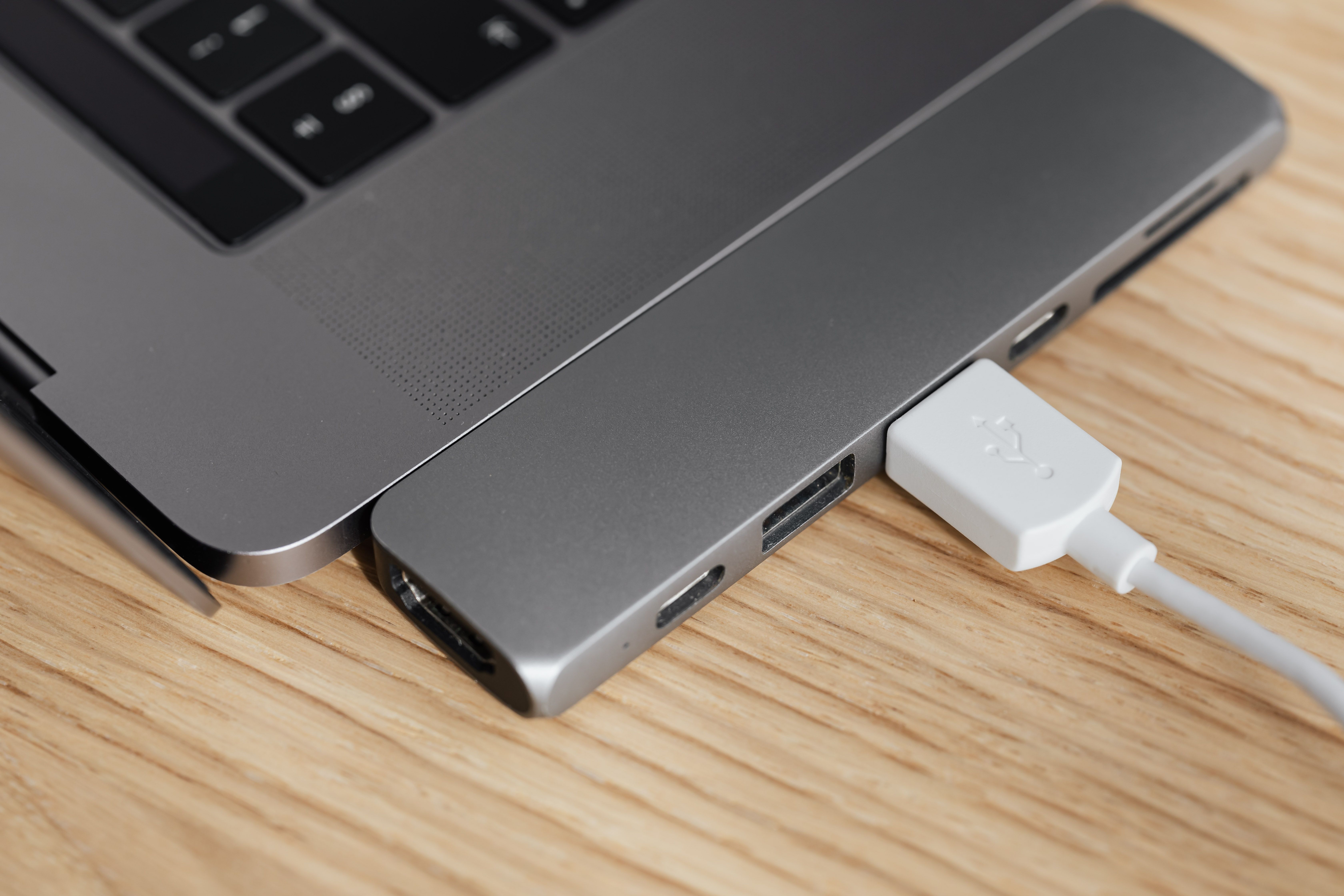 From above of modern USB hub connector under type c for laptop with plugged white cable on wooden table