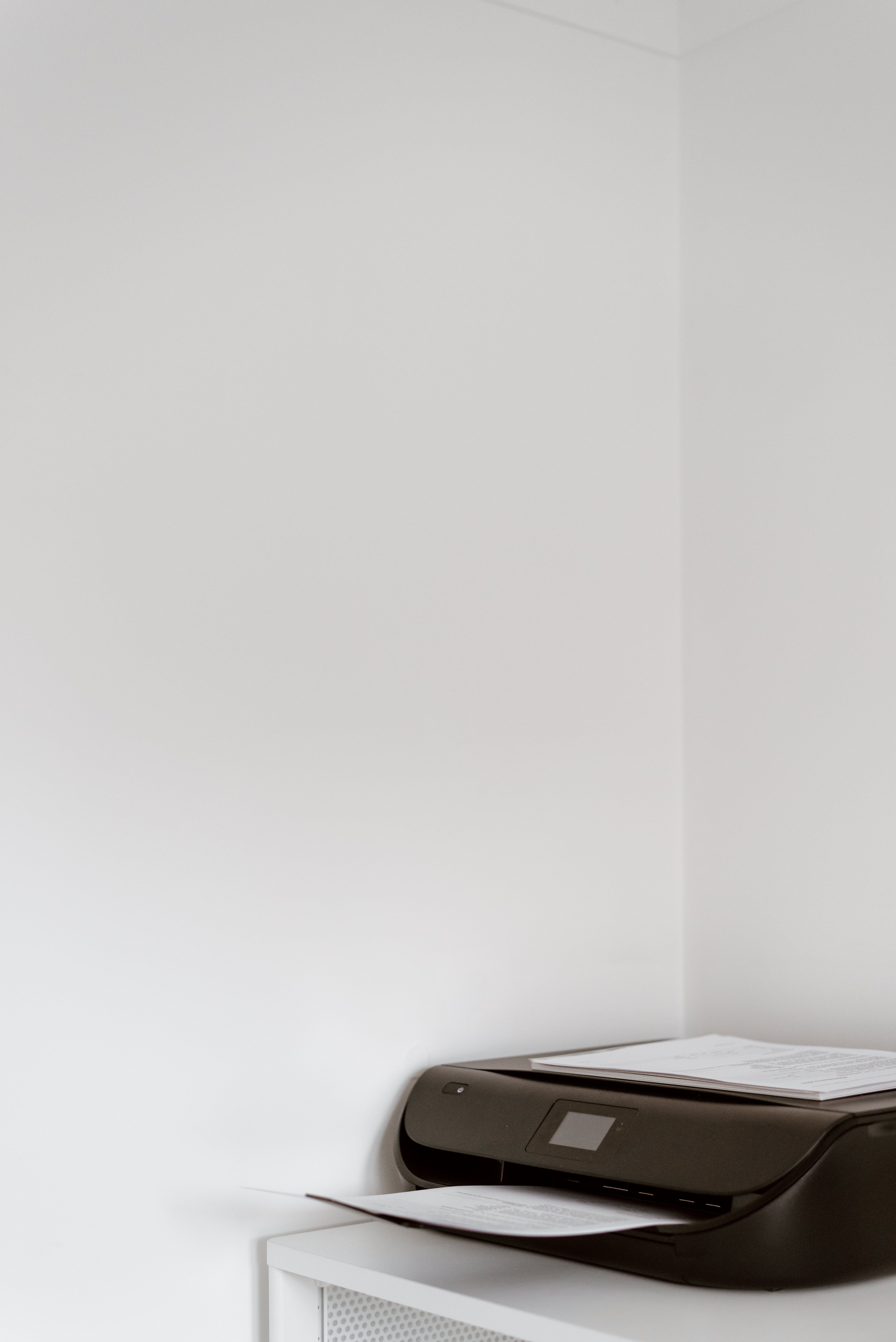 Contemporary printer with blank page placed in corner of cabinet with empty walls