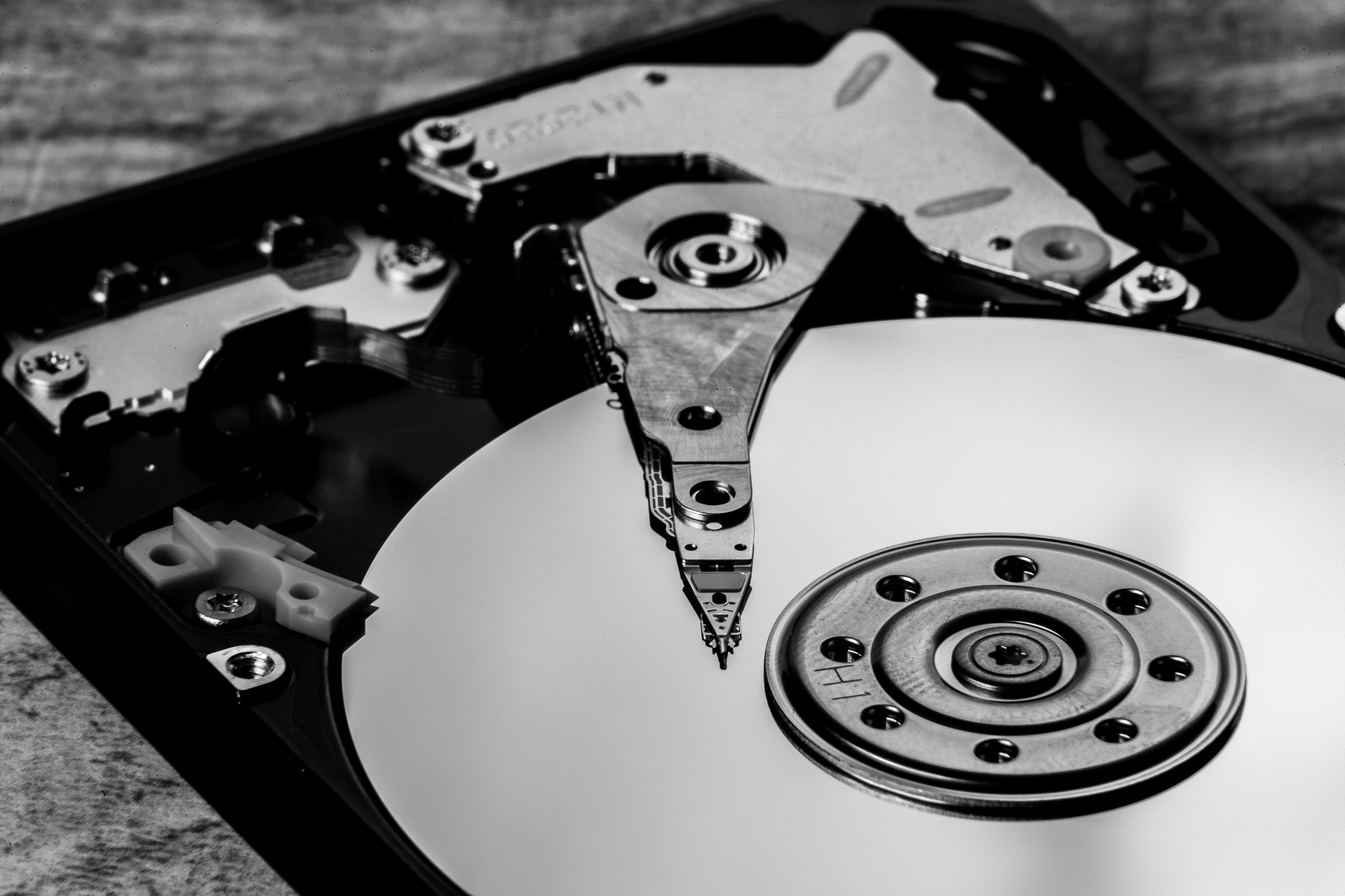 Detailed black and white image of an open hard drive, showcasing intricate components.