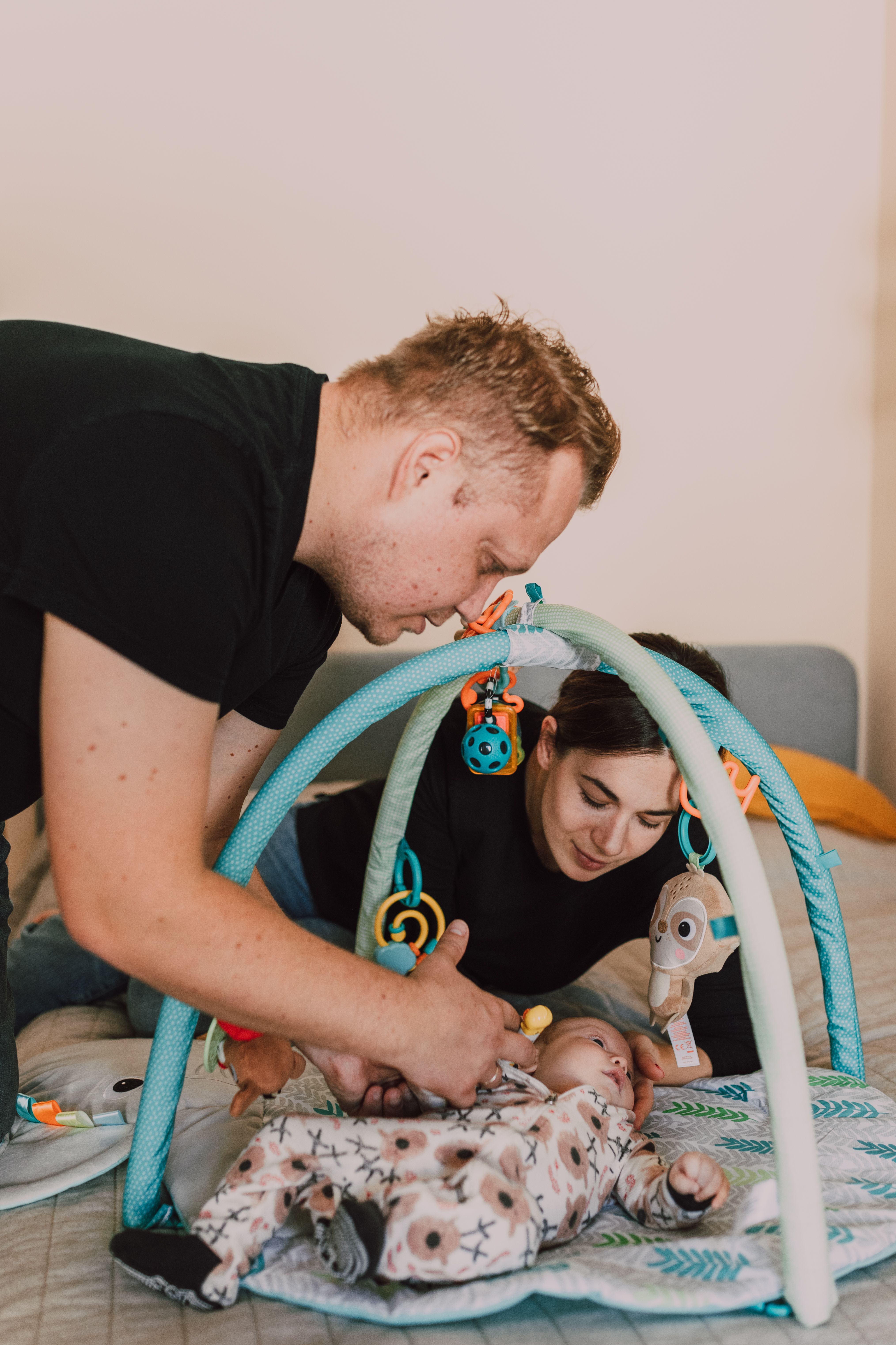 A young couple tenderly playing with their newborn baby in a cozy indoor setting.